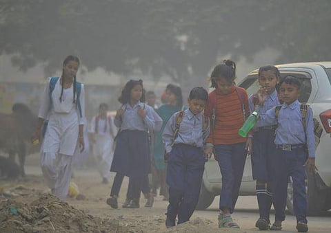 Students walk down a road to their schools amid low visibility due to smog, in Gurugram, on November 3, 2022. (Photo | PTI)