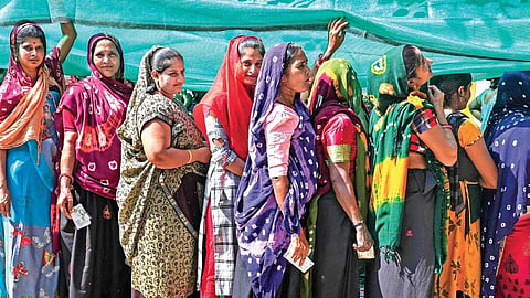 Women wait in a queue to cast their votes at a polling station.