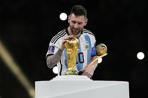 Argentina's Lionel Messi pats the trophy after winning the World Cup final  match against France at the Lusail Stadium in Qatar. (Photo | AP)