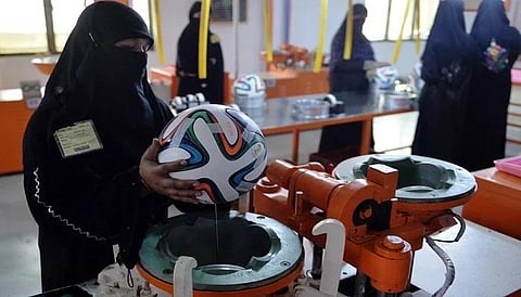 In this backdated image, a worker applies adhesives to the edges of a design on a football at a factory in Sialkot, Pakistan. (Photo |  AFP)