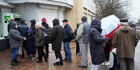 People line up to withdraw their money from an ATM in Mariupol, Ukraine. (Photo | AP)