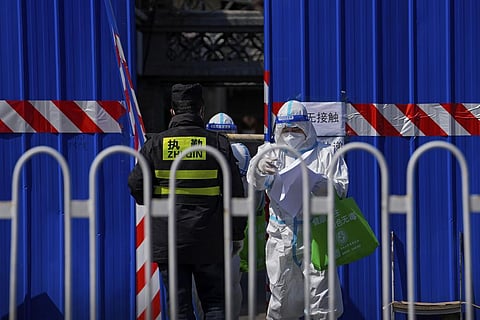 A health worker wearing a protective suit walk out from a barricaded community which was locked down for the COVID-19 case detected in the area. (Photo | AP)