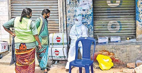 A health worker wearing  a PPE kit speaks to pourakarmikas at Kalasipalya  in Bengaluru (Photo | EPS, Shriram BN)