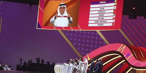 Former Qatari soccer international Adel Ahmed MalAllah holds up the name of Senegal the 2022 soccer World Cup draw at the Doha Exhibition and Convention Center in Doha, April 1, 2022. (Photo | AP)