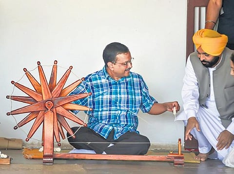 Delhi CM Arvind Kejriwal and Punjab CM Bhagwant Mann spin thread on a ‘charkha’ during their visit to the Sabarmati Ashram on Saturday | PTI