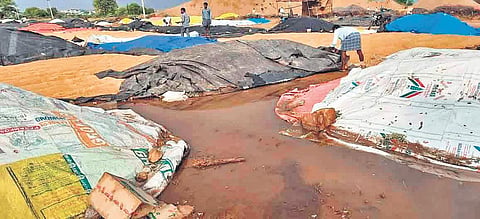 Ryots attempt to save their paddy yield from the stagnant water at a paddy procurement centre in Vemulawada on Monday