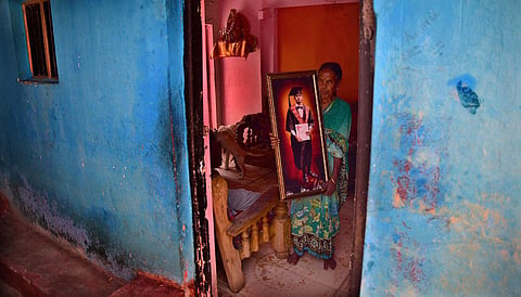 A woman proudly holds a portrait of her grandson who completed MSc in biotechnology at workers’ quarters of Bharath Gold Mine Limited in KGF. (Photo | Shriram BN, EPS)