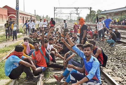 Youngsters sit on railway tracks to protest against the 'Agnipath' scheme, in Buxar. (Photo| PTI)