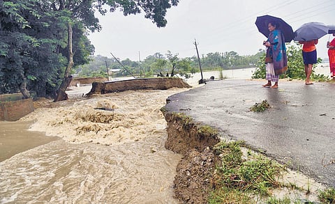 Locals look at a section of a road washed away by flood waters at Dhamdhama in Nalbari district of Assam on  Friday. (Photo | PTI)