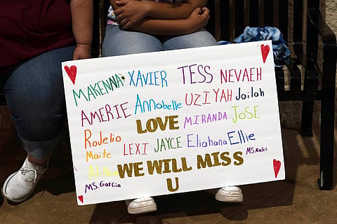 Stormy Flores, 11, sits with a sign bearing the names of the Robb Elementary School shooting victims during a prayer vigil in Uvalde, Texas. (File Photo | AP)