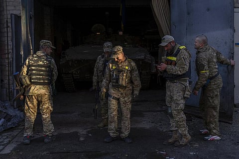 Ukrainian servicemen gather next a Russian BMP-2, an infantry combat vehicle, in the Kharkiv area, eastern Ukraine. (File Photo| AP)
