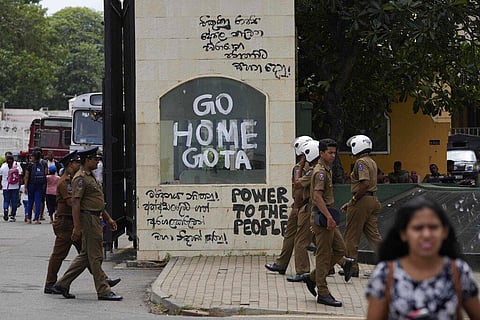 Police officers and people walk past a vandalised entrance to the president's official residence in Colombo, Sri Lanka. (Photo | AP)
