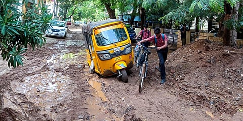 A student struggles with his bicycle on a muddy road at Thillai Nagar in Tiruchy. (Photo| EPS)