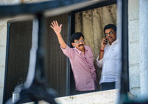 Shiv Sena MP Sanjay Raut waves at his supporters who gathered outside his residence after his premises were raided by ED officials. (Photo | PTI)