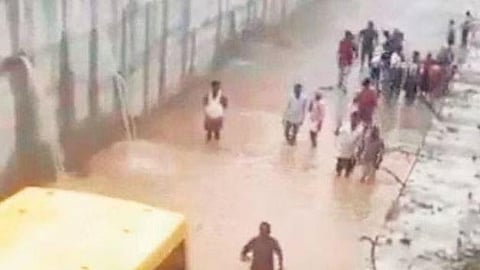 Villagers form a line to safely rescue the 30 students of the Bhashyam Techno School after their school bus stalled while crossing a flooded railway underpass in Mahabubnagar district on Friday mornin