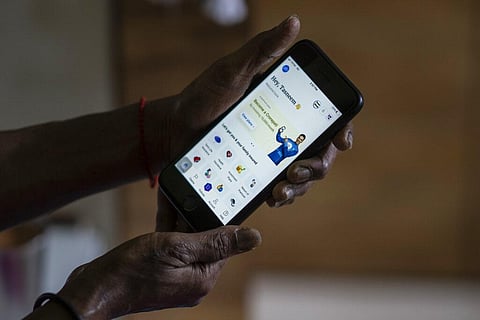 A woman shows her account at policybazaar app on her phone. (Phone | AP)