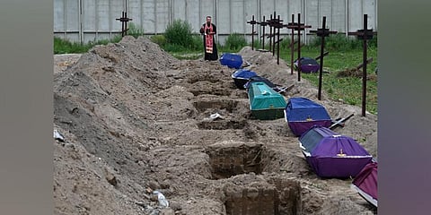 Orthodox priest Andriy Golovin, recites a prayer at the graves of unidentified civilians during their funeral at a local cemetary in the city of Bucha, Kyiv region. (Photo | AP)