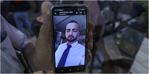 A relative shows his mobile phone displaying a picture of Palestinian Mohammed al-Shaham, 21, killed during an Israeli home raid. (Photo | AFP)