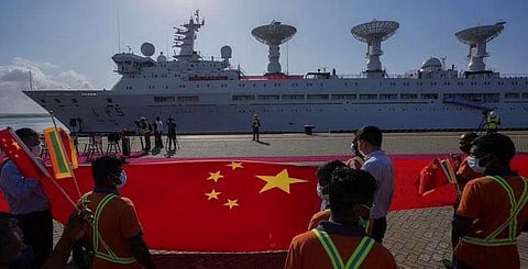 Sri Lankan port workers hold a Chinese national flag to welcome Chinese research ship Yuan Wang 5 as it arrives in Hambantota International Port in Hambantota, Sri Lanka(Photo | AP)