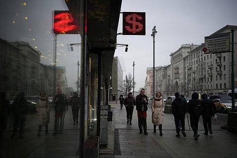 People walk past a currency exchange office screen displaying the exchange rates of U.S. Dollar and Euro to Russian Rubles in Moscow's downtown, Russia, on March 29, 2022. (File photo | AP)