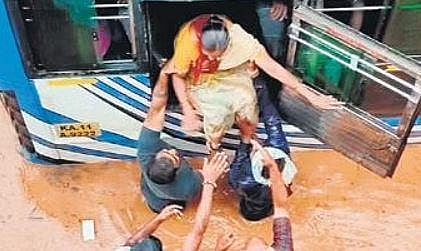 A woman is helped out of a bus on a flooded road in Ramanagara, which saw heavy rain on Monday | Express