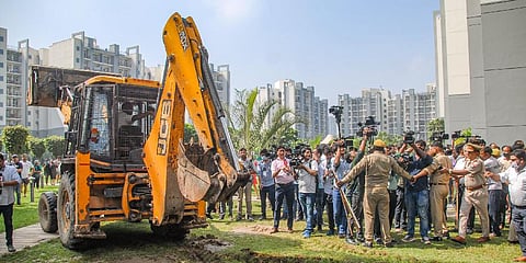 Police personnel guard as a Noida Authority buldozer arrives for the demolition of illegal construction at the Grand Omaxe society, in Noida, on August 8, 2022. (Photo | PTI)