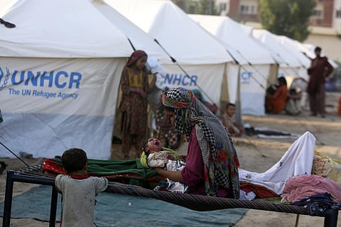A displaced woman hold her newborn baby as she takes refuge at a temporary tent housing camp for flood victims organized by the UN Refugee Agency (UNHCR), in Sukkur, Pakistan. (Photo | AP)