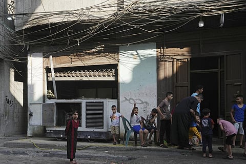 Children hang out near an electricity generator under electricity distribution wires in the Shati refugee camp, Gaza City, July 8, 2022.  (Photo | AP)