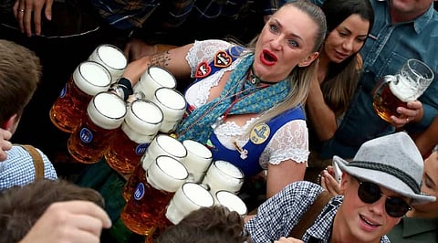 A waitress holds twelve glasses of beer during the opening of the 186th 'Oktoberfest' beer festival in Munich, Germany.  ( Photo |AP)