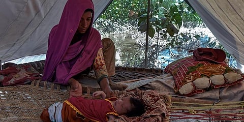 Flood-affected Hajira Bibi sits with her child inside a tent near her flooded house at Jindi village in Charsadda district of Khyber Pakhtunkhwa. (Photo | AFP)
