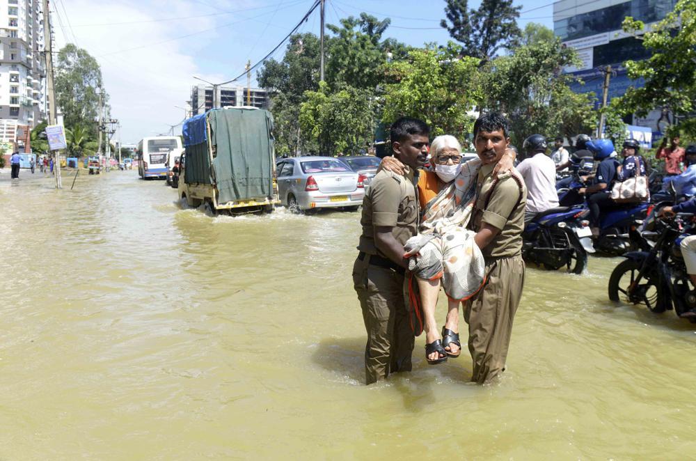 Firefighters help an elderly woman move to a safer area after heavy rainfall in Bangalore, India, Monday, Sept. 5, 2022. (Photo | AP)