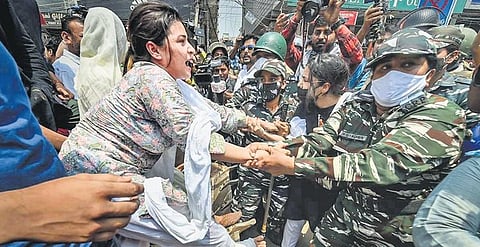 A woman is taken away by security personnel while trying to stop a bulldozer during a protest againt the encroachment drive conducted by the South Delhi Municipal Corporation at Shaheen Bagh in May
