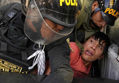 Anti-government protesters who traveled to the capital to march against Peruvian President Dina Boluarte, is detained and thrown on the back of police vehicle during clashes. (Photo | AP)