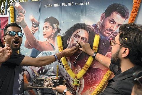 Fans of Bollywood star actor Shah Rukh Khan offer cake to the actor through his photograph as they celebrate the release of his movie 'Pathaan', in Kolkata, (Photo | PTI)