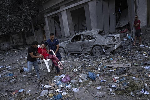 Palestinians walk amid the rubble following Israeli airstrikes that razes swathes of  a neighbourhood in Gaza City, Oct 10, 2023. (Photo | AP)