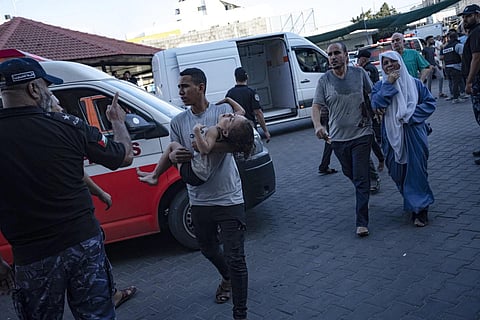 A Palestinian man carries a wounded girl into Shifa hospital in Gaza City, Oct 10, 2023. (Photo | AP)