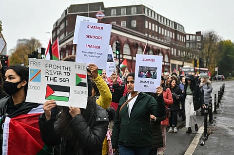 Protesters hold placards reading a message for Britain's Labour leader Keir Starmer as they walk past his office during the 'Day of Action for Palestine”, a march from Chalk Farm to Camden Town | AFP