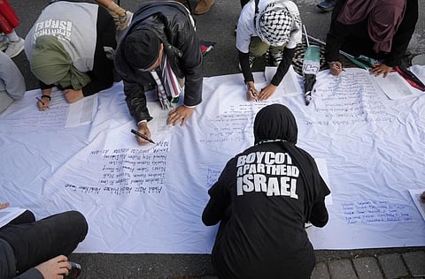Pro-Palestinian supporters write names of lives lost in the war, as they protest outside Parliament in Cape Town, South Africa,  Nov 21, 2023. (Photo | AP)