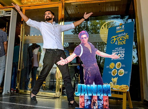 FILE: A fan of Bollywood actor Shah Rukh Khan poses with the poster of Jawan movie. (PTI)