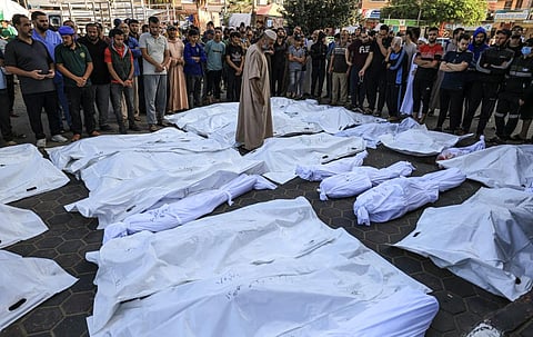A man walks between the bodies wrapped in shrouds of those killed in Israeli bombardment in Deir Balah in the central Gaza Strip.