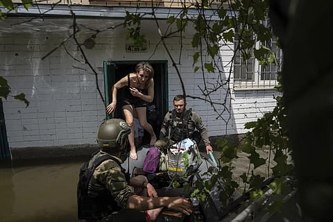 Local resident Olena gets on a small boat as she is evacuated by Ukrainian servicemen from a flooded neighborhood in Kherson, Ukraine. (Photo | AP)