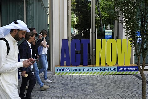 A group walks near a sign that reads 'act now' at the COP28 UN Climate Summit, Sunday, Dec. 10, 2023, in Dubai, United Arab Emirates. (AP Photo)