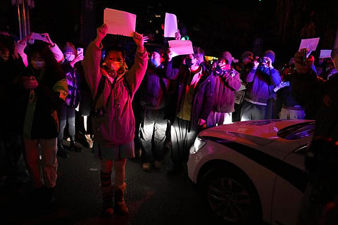 FILE - Protesters hold up blank papers and chant slogans as they march in protest in Beijing, Nov. 27, 2022.  (Photo | AP)