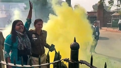 Police personnel detain a woman protesting outside the Parliament building carrying a can emitting a yellowish smoke during the Winter session, in New Delhi. (Photo | PTI)