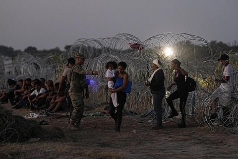 FILE - Migrants who crossed the Rio Grande and entered the US from Mexico are lined up for processing by US Customs and Border Protection, Saturday, Sept 23, 2023. (Photo | AP)