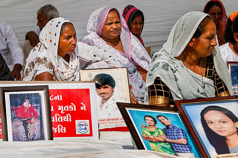 FILE: Family members holding pictures of relatives who lost their lives in the Morbi bridge collapse, stage a protest on the first anniversary of the incident, in Ahmedabad. (PTI)