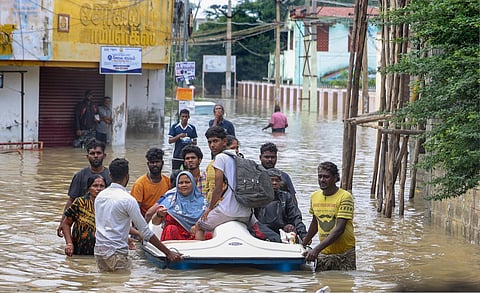 People shift from a flooded road after heavy rainfall in Thoothukudi district