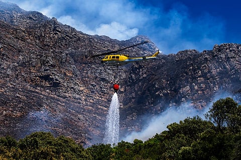A fire fighting helicopter battles a vegetation fire on the slopes above Simon's Town, around 40 kilometers (25 miles) south of Cape Town, South Africa, Tuesday, December 19, 2023. (Photo | AP)