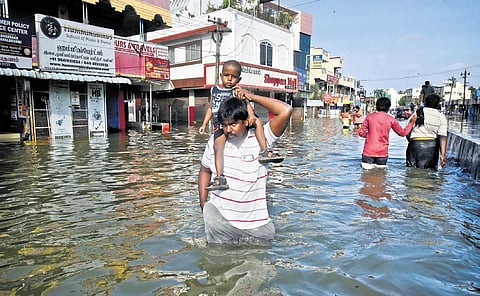 People wade through flooded streets at Mudichur | P Ravikumar
