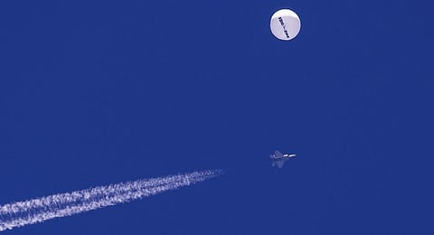 A large balloon drifts above the Atlantic Ocean, just off the coast of South Carolina, with a fighter jet and its contrail seen below it. (Photo | AP)